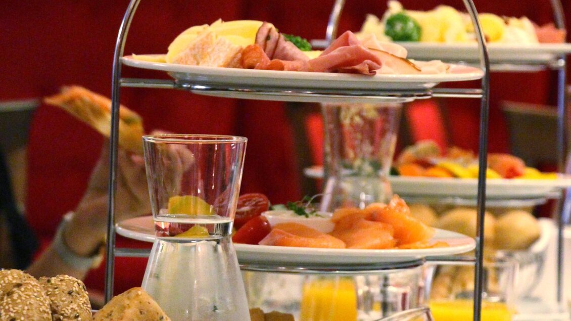 Mehrstöckige Etagere mit Brötchen, Käse, Aufschnitt, Räucherlachs und frischem Obst, dazu Gläser mit Orangensaft und Wasser | © Region Graz - Vanessa Züttl