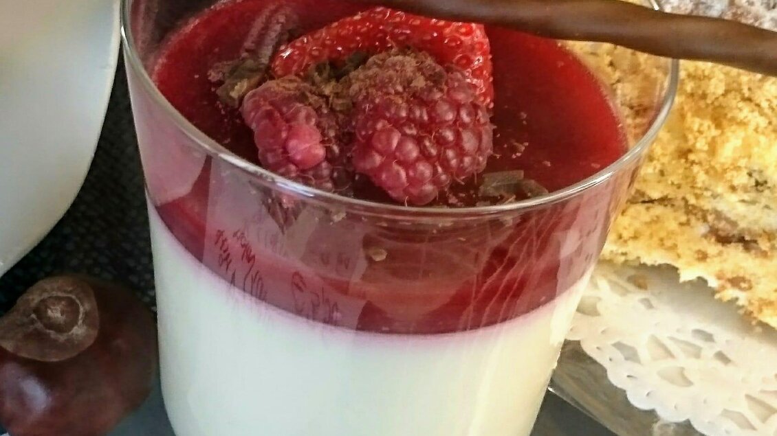 Ein leckeres Dessert in einem Glas mit einer Schicht aus Joghurt und fruchtiger Himbeersauce. Dekoriert mit frischen Himbeeren und einem Schokoladenstick. | © Café Idylle