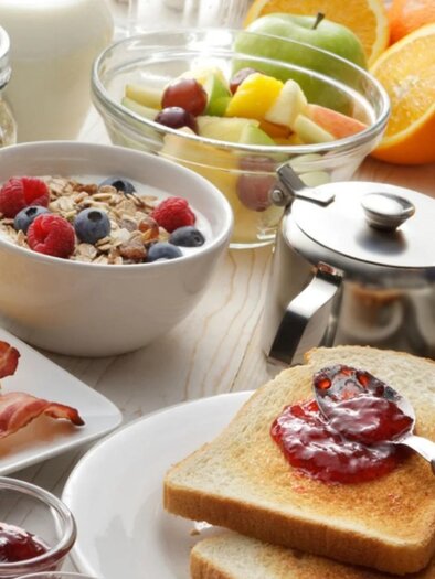 Breakfast table with toast and jam, scrambled eggs with bacon, muesli, fruit, juice, and coffee. | © Café Muhr