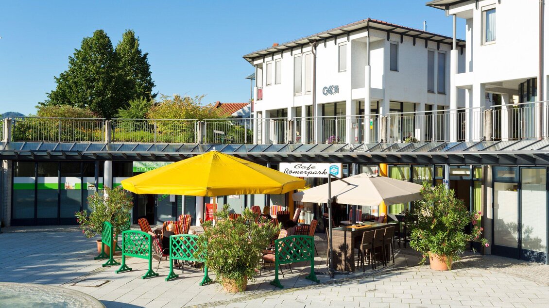 Eine sonnige Terrasse mit Stühlen und Schirmen. Im Hintergrund ist ein modernes Gebäude mit Bäumen zu sehen. | © TV Region Graz - René Vidalli