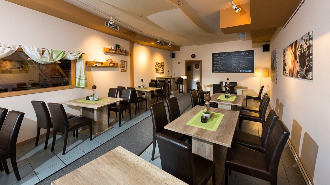 Ein gemütliches Restaurant mit Holzstühlen und Tischen. Die Wände sind geschmückt mit Bildern, und es gibt eine Tafel mit Beschreibungen. | © TV Region Graz - René Vidalli