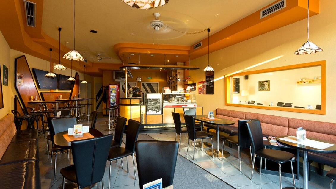 Ein modernes Café mit eleganten Tischen und Stühlen. Die Wände sind in warmen Farben gehalten und es gibt eine einladende Atmosphäre. | © TV Region Graz - René Vidalli