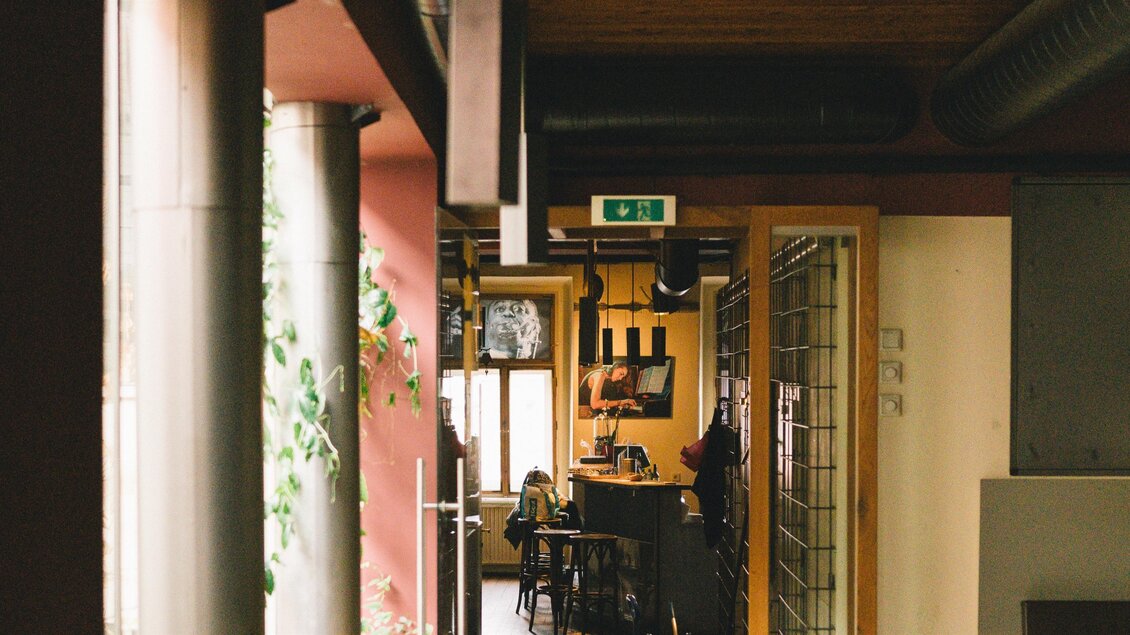 Ein gemütlicher Innenraum mit Holz- und Metallelementen. Im Hintergrund sind Tische und Stühle zu sehen, die eine einladende Atmosphäre schaffen. | © Cafe Stockwerk - G. Obetzhofer