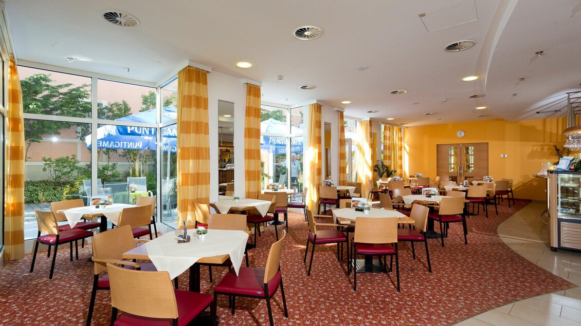 Ein einladendes Restaurant mit hellen Wänden und großen Fenstern. Die Tische sind ordentlich mit weißen Tischdecken gedeckt und der Raum wirkt freundlich und hell. | © TV Region Graz - René Vidalli