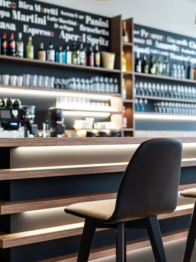 Eine elegante Bar mit einer gut sortierten Getränkeauswahl und stilvollen Sitzplätzen. Der moderne Raum strahlt eine einladende Atmosphäre aus. | © Kalthuber photography