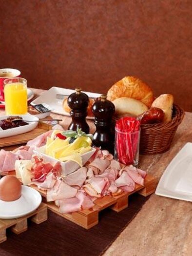 Ein schön gedeckter Tisch mit verschiedenen Frühstücksoptionen. Es gibt frische Brötchen, Aufschnitt, Eier und Getränke. | © Barletti