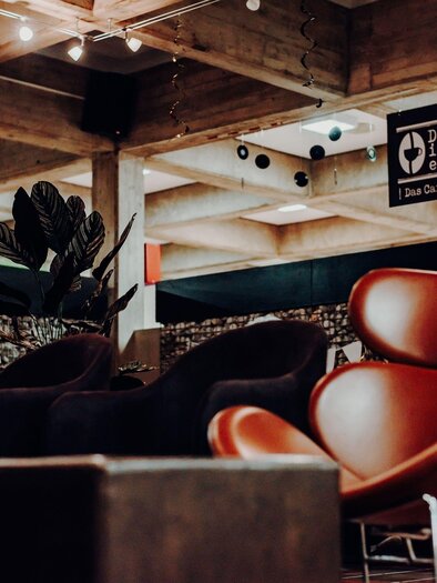 A cozy interior with modern furniture and an inviting atmosphere. In the background, a sign with the name "Chillerei" can be seen. | © GenussReich