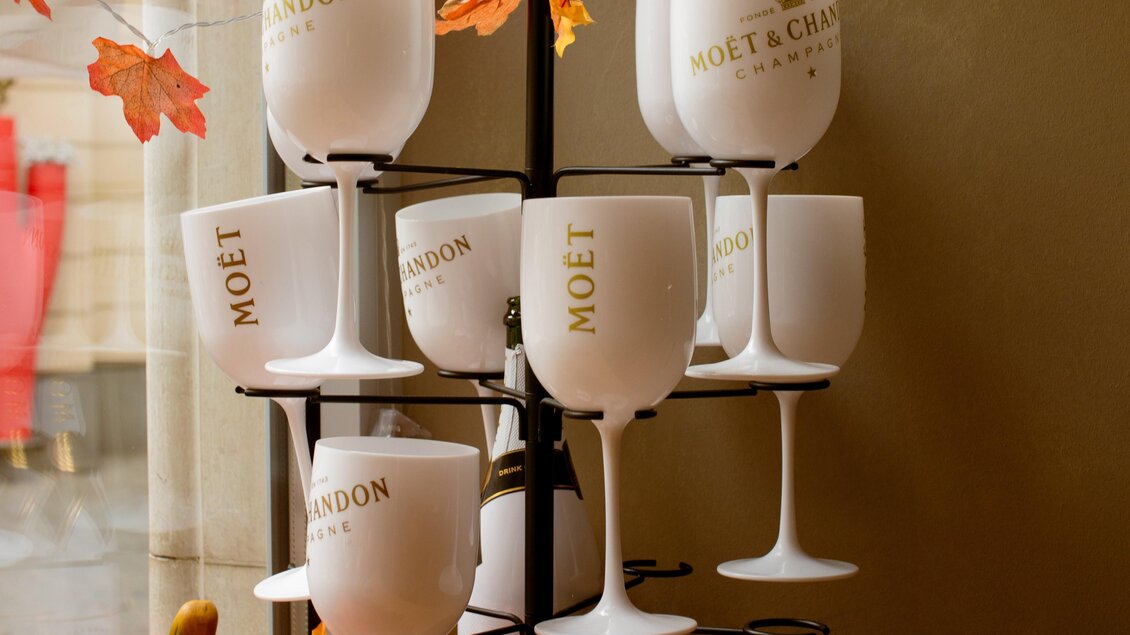 Ein eleganter Ständer mit weißen Gläsern von Moët & Chandon. Im Hintergrund sind herbstliche Blätter und dekorative Elemente zu sehen. | © Amaro