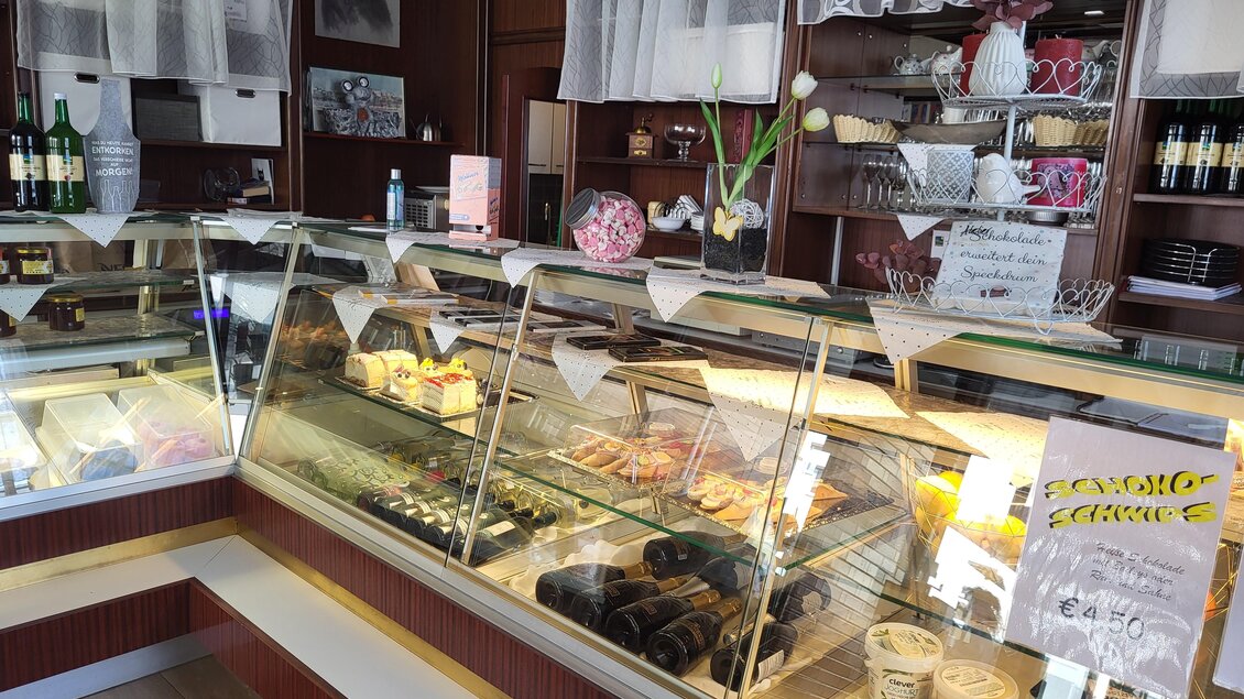 Eine Bäckerei mit einer Vitrine voller leckerer Gebäckstücke und Torten. Im Hintergrund sind einige Flaschen und Dekorationen zu sehen. | © TV Hochsteiermark