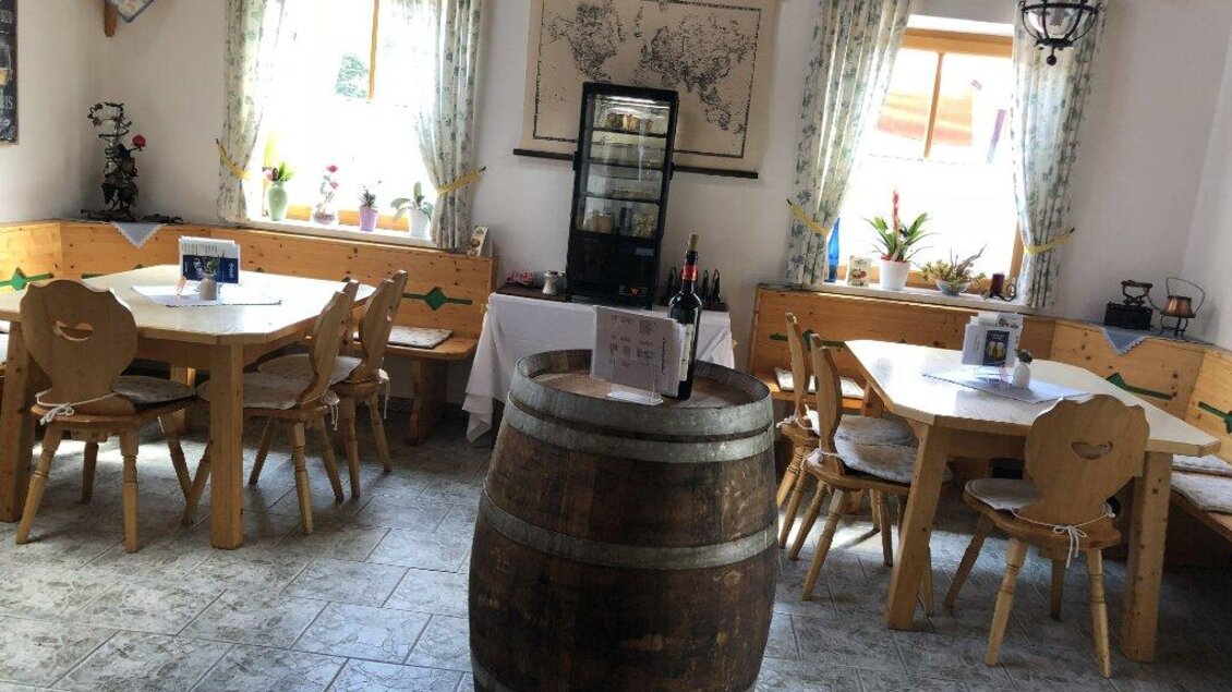 Ein gemütliches Restaurant mit Holztischen und Bänken. Große Fenster lassen viel Licht herein und es gibt eine Holzfasade mit rustikalem Charme.