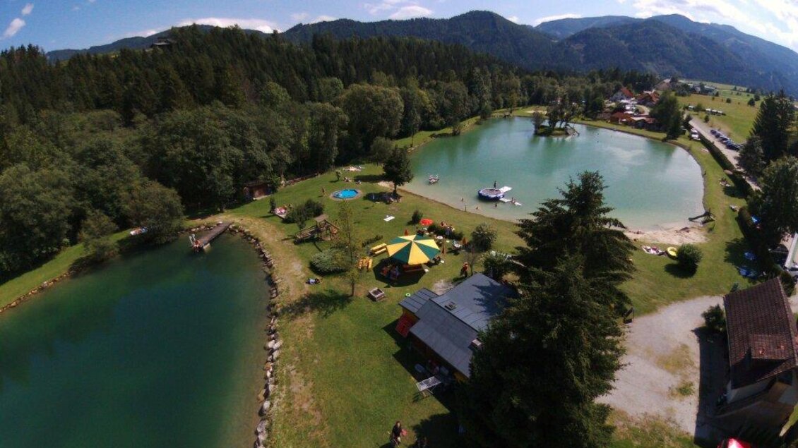Eine schöne Landschaft mit zwei klaren Seen und viel grünem Gras. Im Hintergrund sind Wälder und Berge zu sehen.