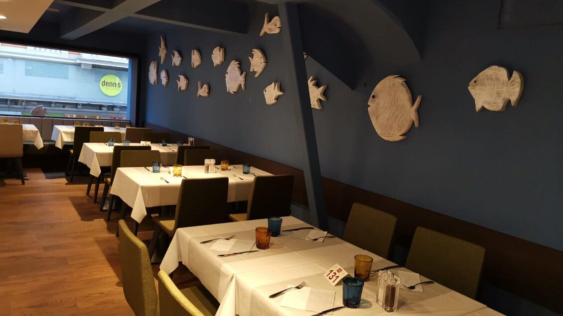 Ein gemütliches Restaurant mit Tischdecken und Stühlen. An der Wand sind Fischdekorationen zu sehen. | © Casa Costiera