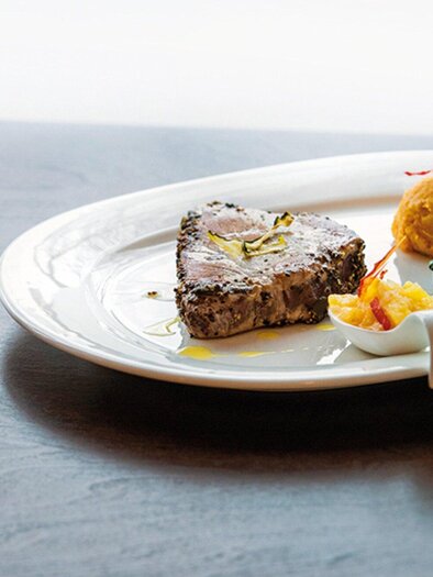 Ein elegant angerichtetes Gericht auf einem weißen Teller. Es besteht aus einem Stück Fleisch, Beilagen und Gewürzmühlen. | © Caylend - Michael Fiedler