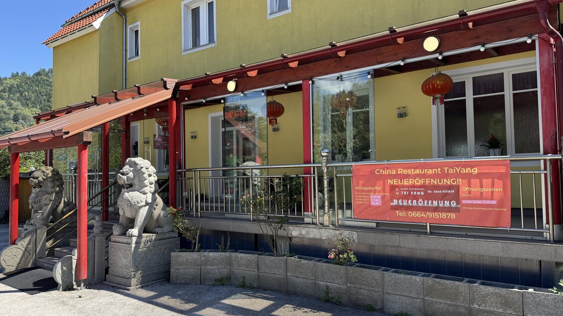 Ein chinesisches Restaurant mit einer großen, gelben Fassade und roten Laternen. Vor dem Eingang stehen zwei Löwenstatuen und ein Banner zur Neueröffnung. | © TV Hochsteiermark