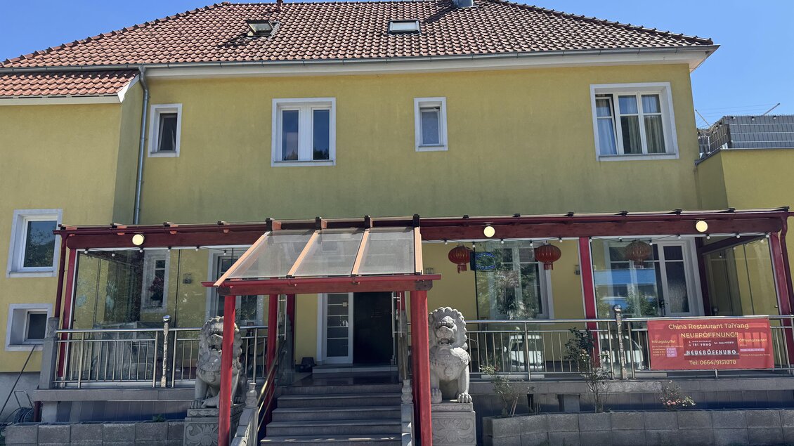 Ein gelbes Gebäude mit einer überdachten Terrasse. An der Vorderseite stehen zwei Steinlöwen. | © TV Hochsteiermark