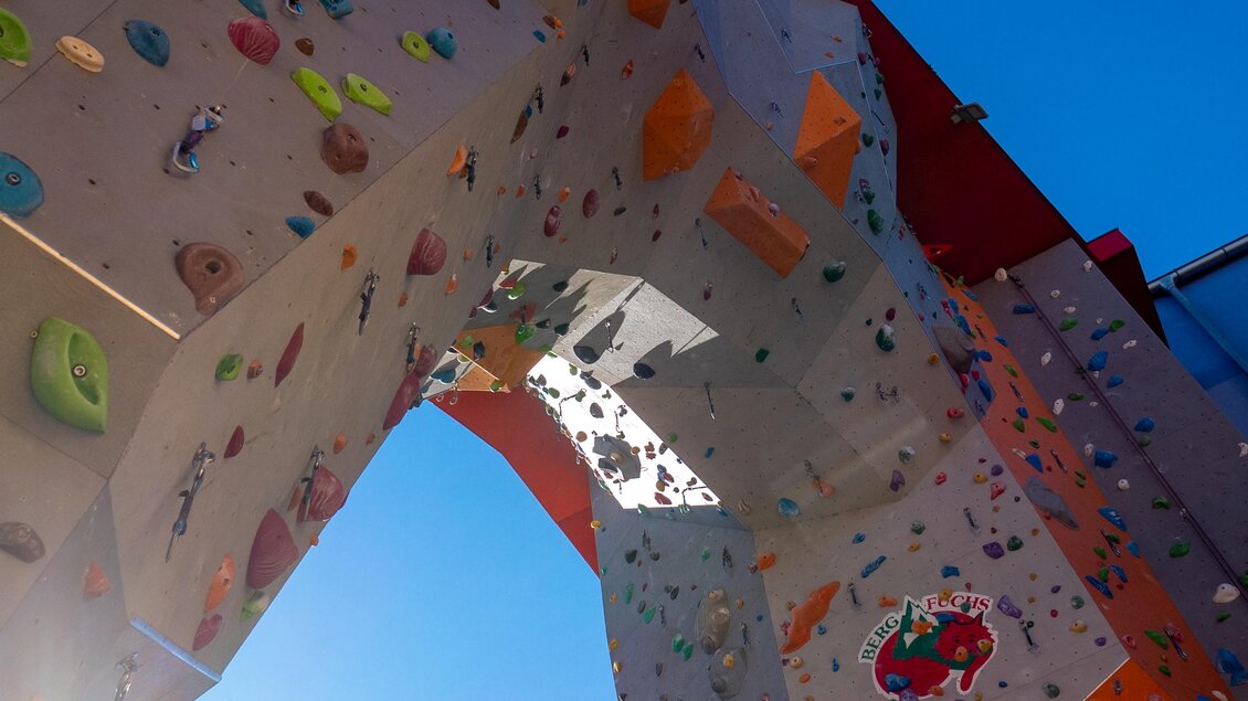 Blick nach oben auf hohen Outdoor-Kletterturm mit bunten Griffen in Graz | © C-A-C