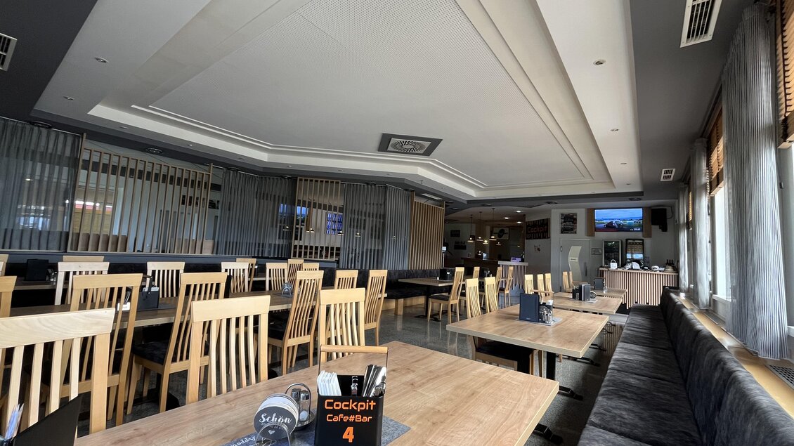 Ein modernes Restaurant mit zahlreichen Holztischen und Stühlen. Die Einrichtung ist hell und freundlich, mit Fenstern, die natürliches Licht hereinscheinen lassen. | © Peter Hopf