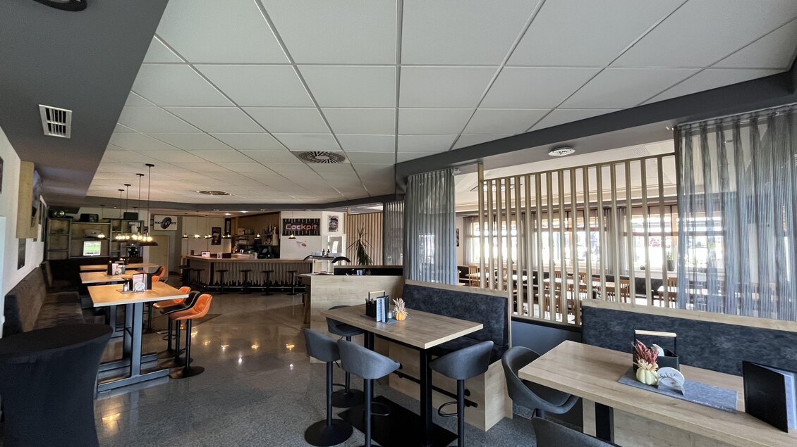 Ein modernes Restaurant mit stilvollen Tischen und Stühlen. Der Bereich ist hell und einladend, mit einer klaren Sicht auf die Bar. | © Peter Hopf