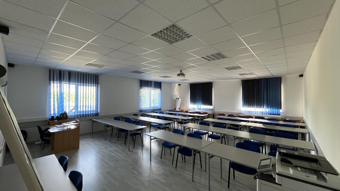 Ein leerer Klassenraum mit Tischen und blauen Stühlen. Die Wände sind hell und die Fenster lassen viel Licht herein. | © Peter Hopf