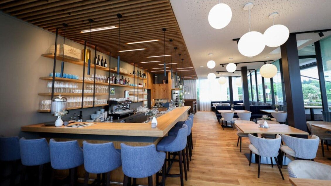 Ein modernes Restaurant mit einer Holzbar und gemütlichen Sitzplätzen. Große Fenster bieten einen Blick ins Freie, während stilvolle Leuchten eine angenehme Atmosphäre schaffen. | © Das Franz