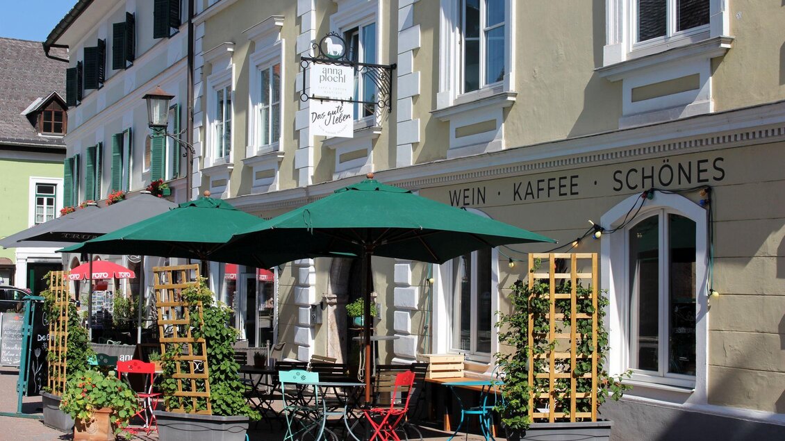 Ein gemütliches Café mit grünen Markisen und bunten Tischen. Im Hintergrund sind schöne Gebäude und frische Pflanzen zu sehen. | © TVB Ausseerland - Salzkammergut_Viola Lechner