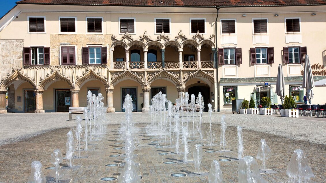 Ein malerischer Platz mit einem beeindruckenden Brunnen und historischen Gebäuden. Die Atmosphäre ist lebhaft und einladend. | © A. Steininger