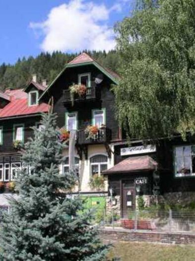 Ein hübsches Hotelgebäude im traditionellen Stil, umgeben von Bäumen. Der Himmel ist blau und die Landschaft ist bergig. | © Fam. Rottenschlager