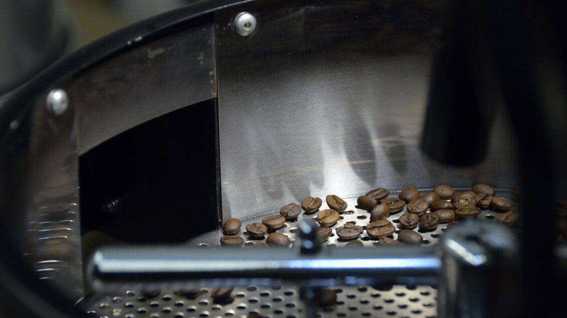 Röstmaschinen mit frisch gerösteten Kaffeebohnen. Die Bohnen liegen auf einem metallischen Gitter.