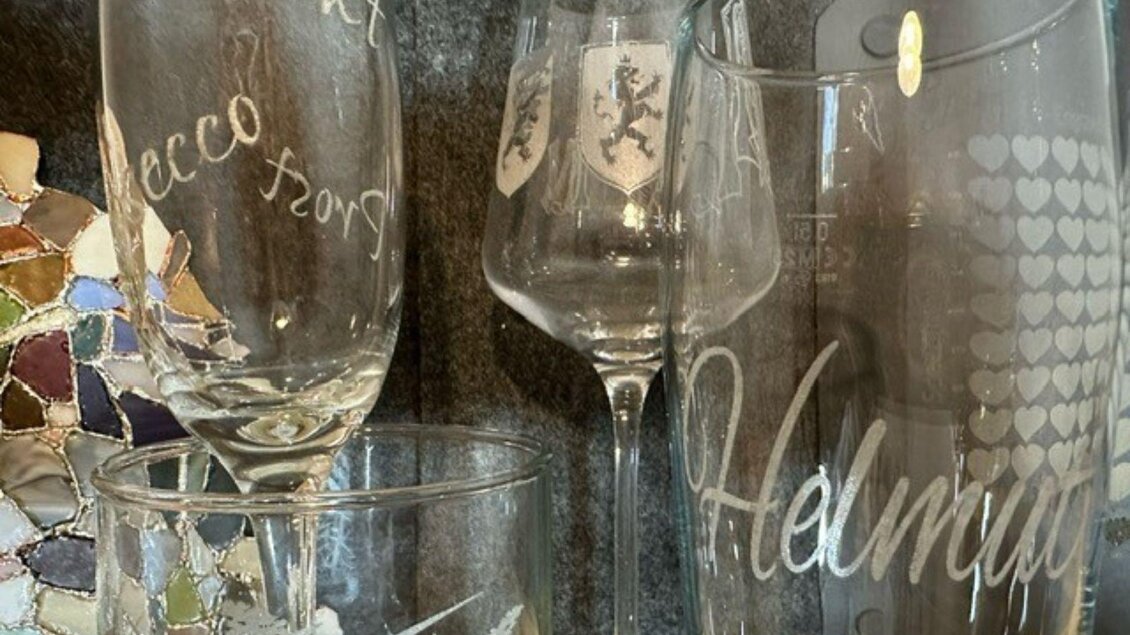 Eine Sammlung von Gläsern, darunter Sektflöten und ein Weinglas mit verschiedenen Designs. Einige Gläser sind graviert, darunter der Name "Helmi." | © Angelika Mikula-Hubacek
