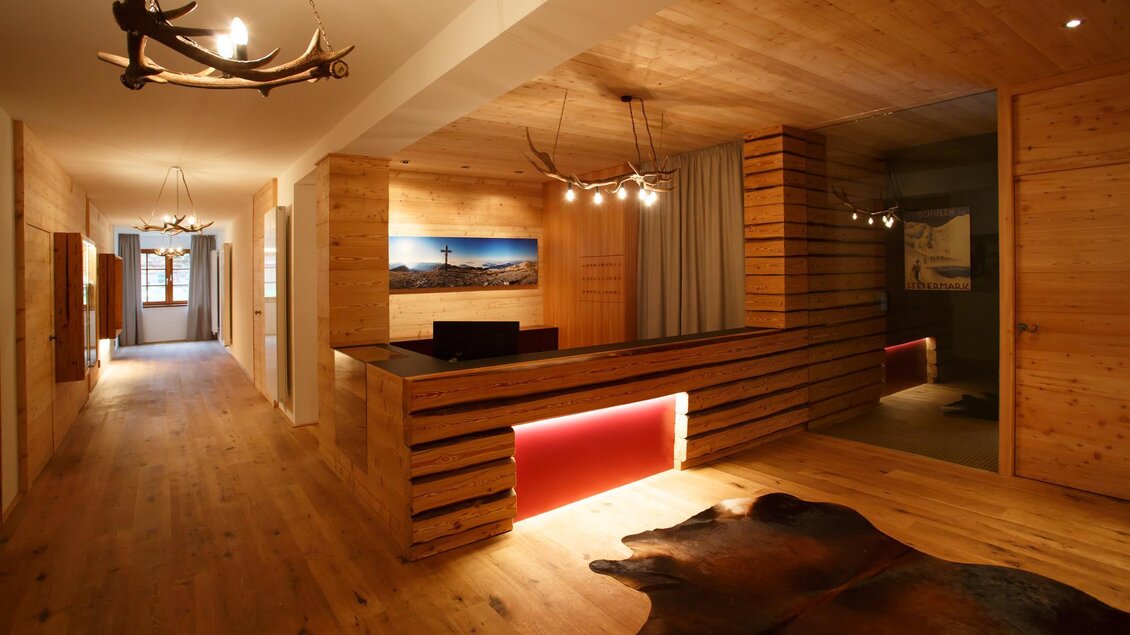 Ein modernes Empfangsbereich mit Holzverkleidung und warmem Licht. Der Boden ist aus Holz und ein Teppich liegt im Vordergrund.