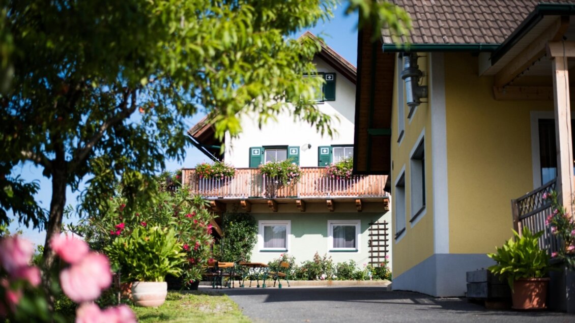 Ein charmantes Haus mit blühenden Pflanzen und einem klaren blauen Himmel. Der Eingangsbereich ist hell und einladend. | © Fam. Hernach | Der Hermannhof