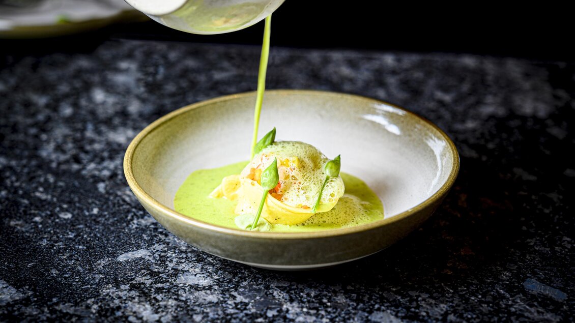 Eine elegante Schüssel mit einer appetitlichen Vorspeise. Eine grüne Sauce wird über die Zutaten gegossen, die frisch und fein präsentiert sind. | © Der Literwirt