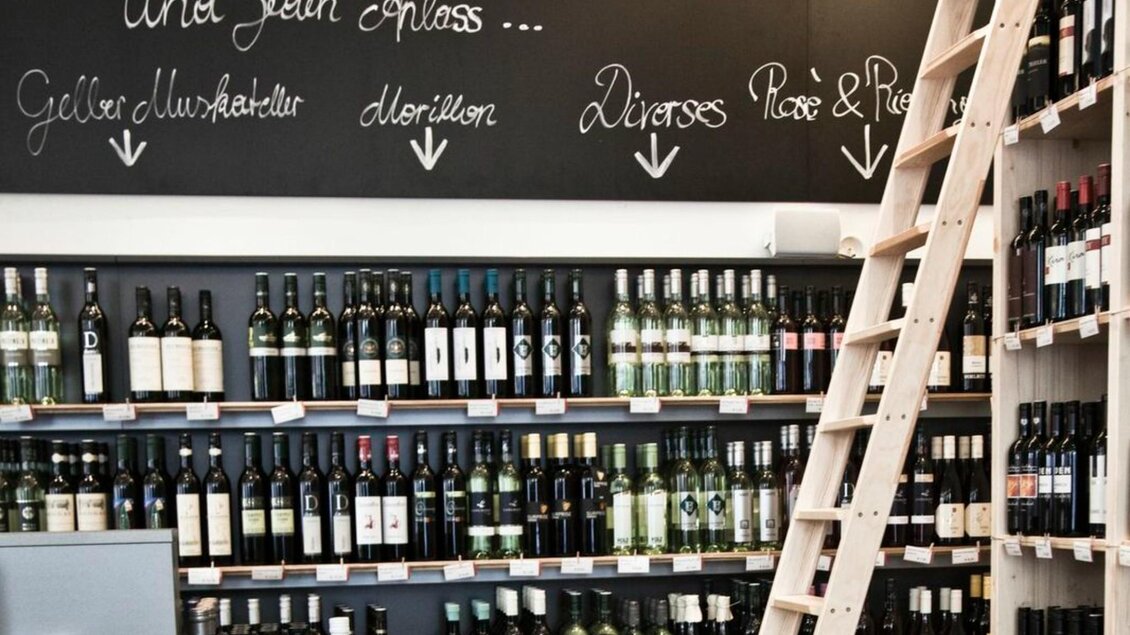 Weinregale im Steirer mit verschiedenen Weinen und einer Holzleiter, beschriftet mit „Und jeden Anlass...“.  | © Weitzer