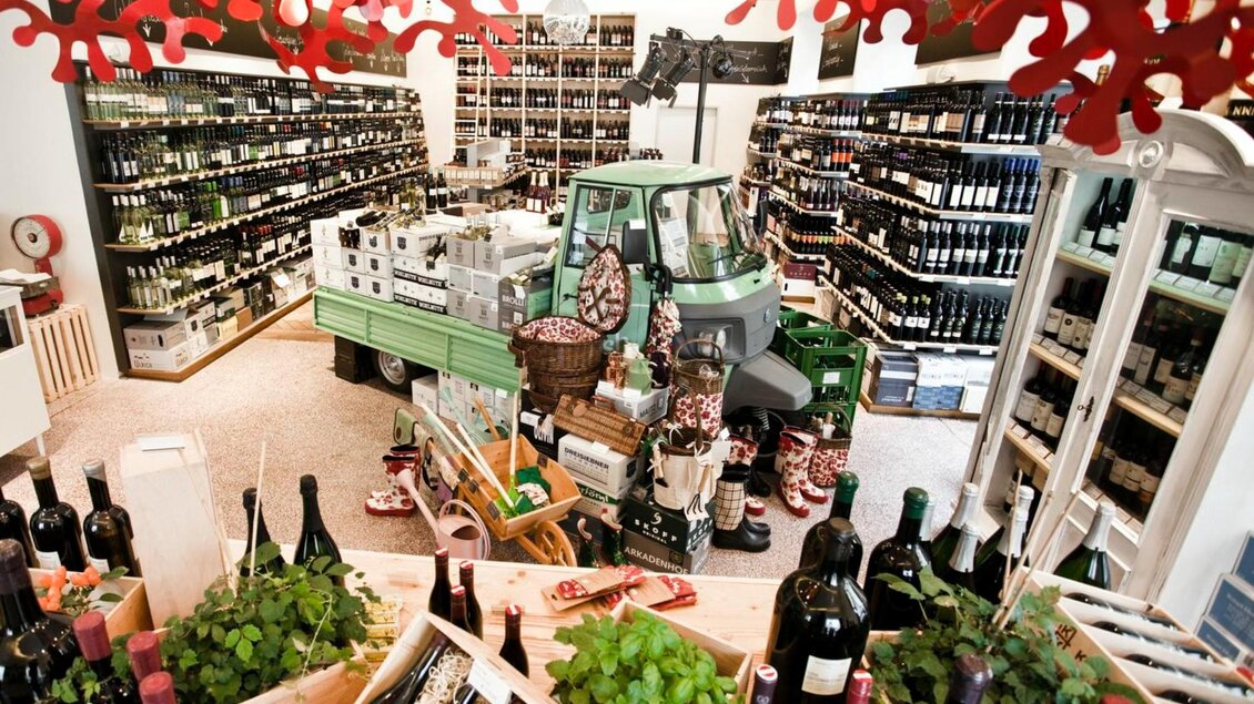 Der Steirer Weinshop mit Regalen voller Weinflaschen und Dekoration, darunter ein grüner Transporter.  | © Weitzer