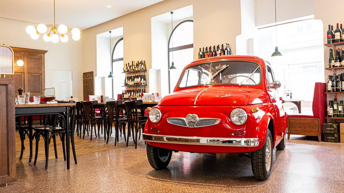 Innenansicht eines Restaurants mit rotem Fiat 500, Holzregalen und eleganter Einrichtung. | © Weitzer