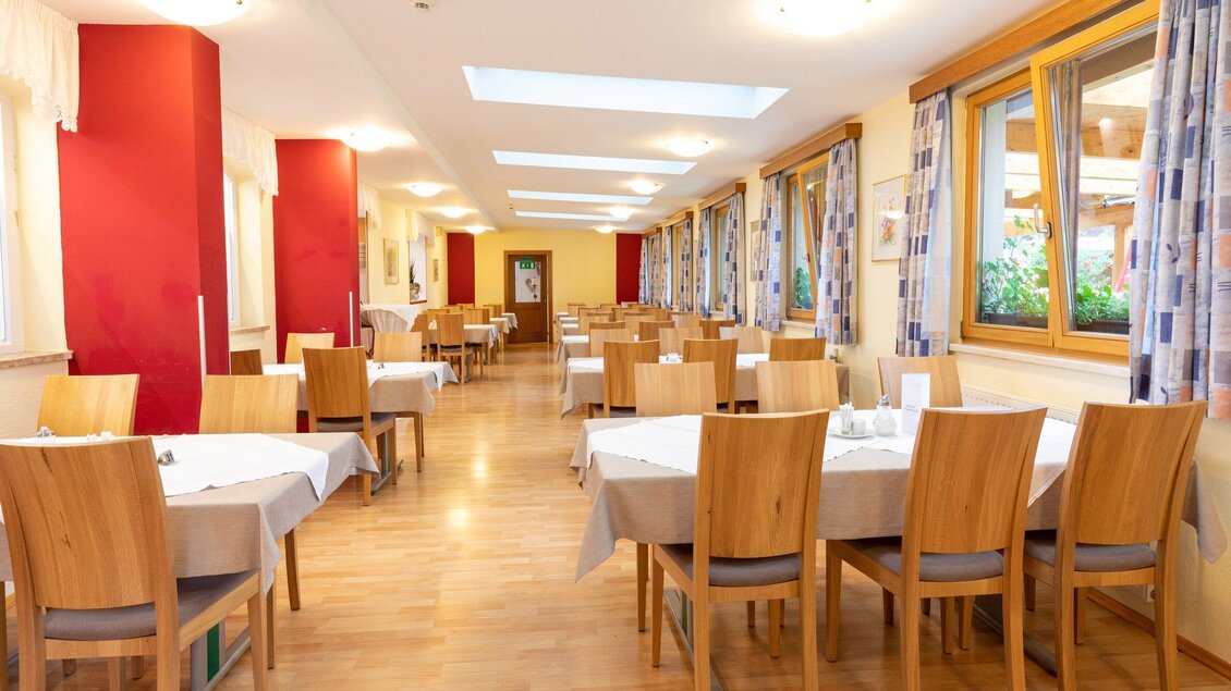 Ein heller Speisesaal mit Holztischen und Stühlen. Große Fenster sorgen für viel Tageslicht und eine freundliche Atmosphäre. | © TV Region Graz - Harry Schiffer