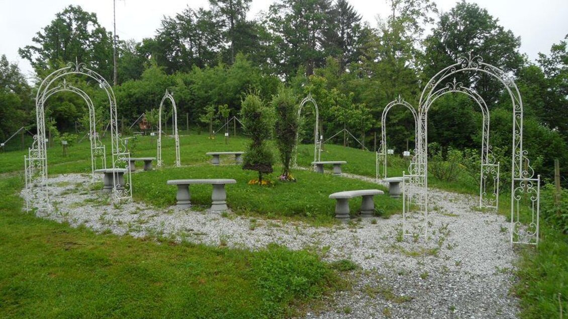 Ein idyllischer Garten mit geschwungenen Wegen, Bänken und dekorativen Bögen. Üppiges Grün und Bäume umgeben den ruhigen Ort. | © TV Lipizzanerheimat/EU