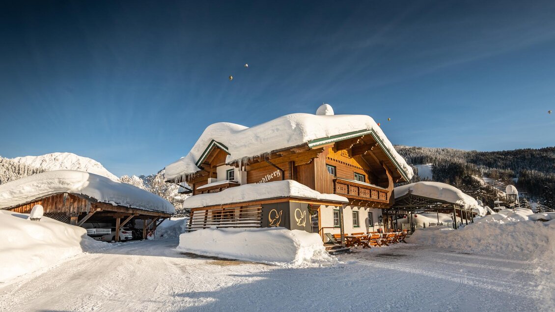 Ein charmantes Chalet im Schnee, umgeben von einer winterlichen Landschaft. Der klare Himmel und die schneebedeckten Dächer verleihen dem Bild eine idyllische Atmosphäre. | © Lorenz Masser