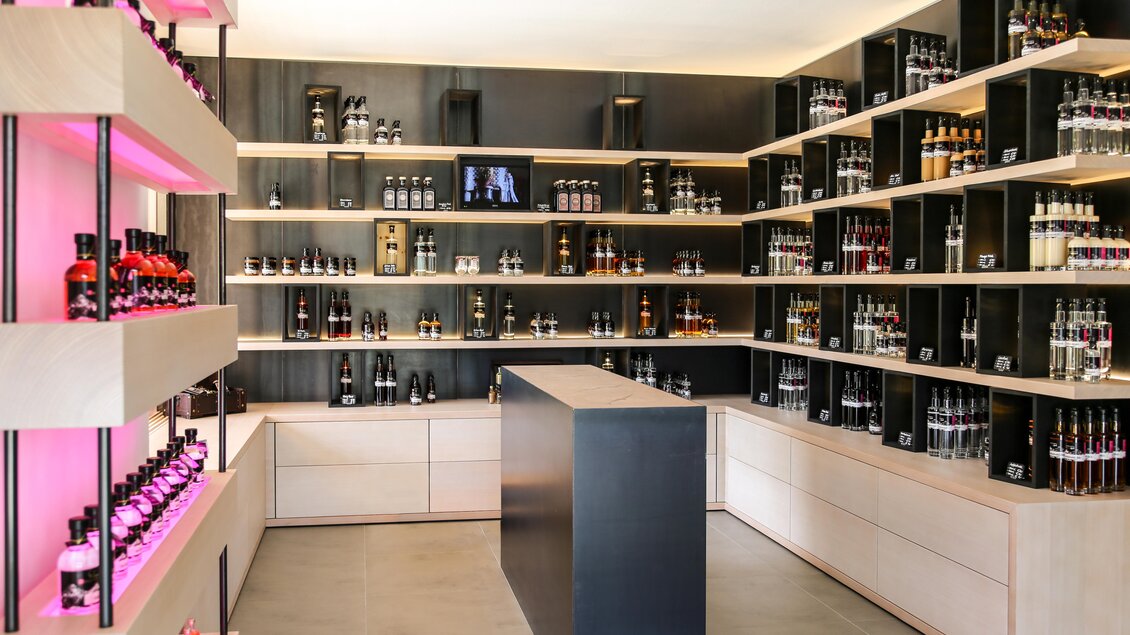 Ein modern gestalteter Verkaufsraum mit Regalen voller Flaschen. Die Wände sind schwarz mit einem hellen Holztheke in der Mitte. | © Mandlberggut