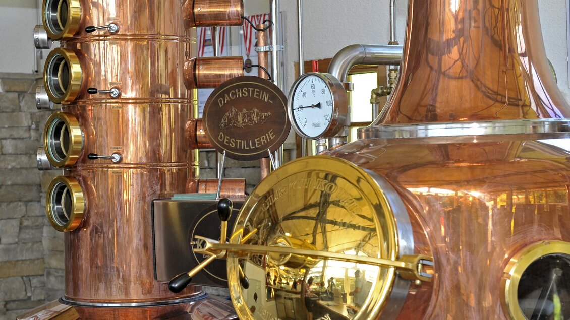 Eine Kupferdestillieranlage mit glänzenden Oberflächen und einem Ziffernblatt. Im Hintergrund sind weitere Ausstattungen der Destillerie sichtbar. | © Shooting Star