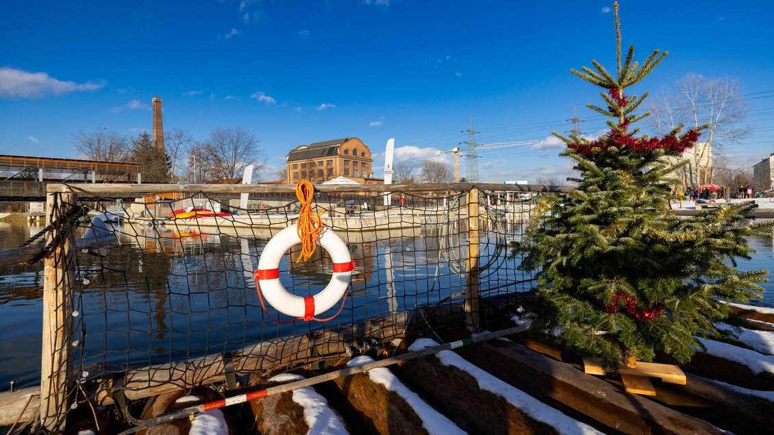 Flossfahrt im Winter auf der Mur, mit Weihnachtsbaum an Bord und Rettungring daneben.  | © Region Graz-Harry Schiffer