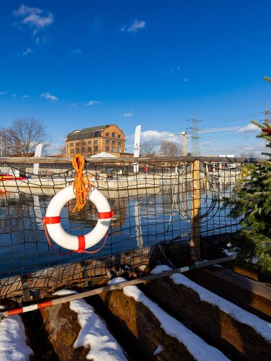 Winter boat trip on the Mur, with a Christmas tree on board and a lifebuoy beside it. | © Region Graz-Harry Schiffer