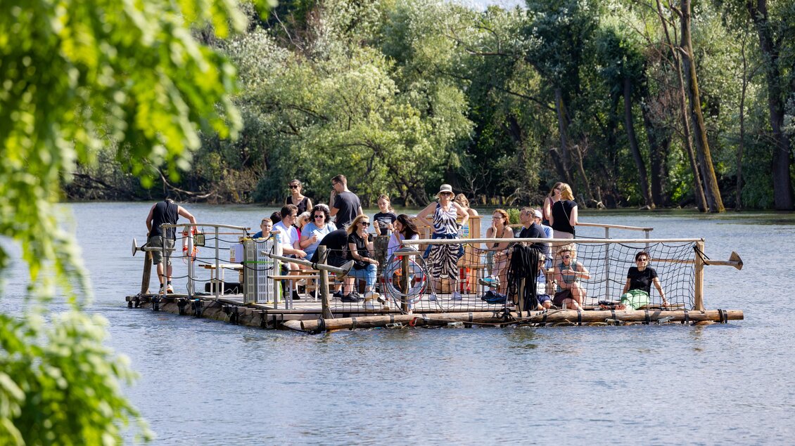 Gruppe bei geführter Flossfahrt auf der Mur, umgeben von Flusslandschaft in Graz. | © Die Flösserei-Harry Schifer