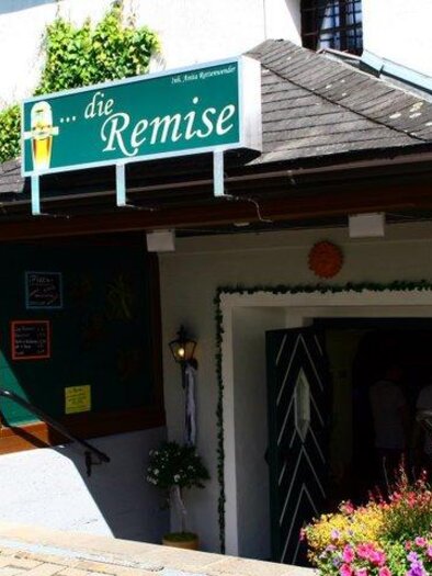 Ein einladender Eingang zu einem Restaurant namens "die Remise". Der Bereich ist mit bunten Blumen und einer Tafel dekoriert.
 | © Die Remise