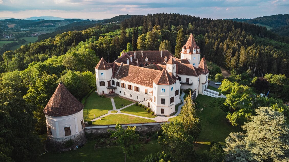 Ein majestätisches Schloss umgeben von üppigem Grün und sanften Hügeln. Die märchenhaften Türme und die sorgfältig gestaltete Gartenanlage verleihen dem Bild einen bezaubernden Charme. | © Thermen- & Vulkanland