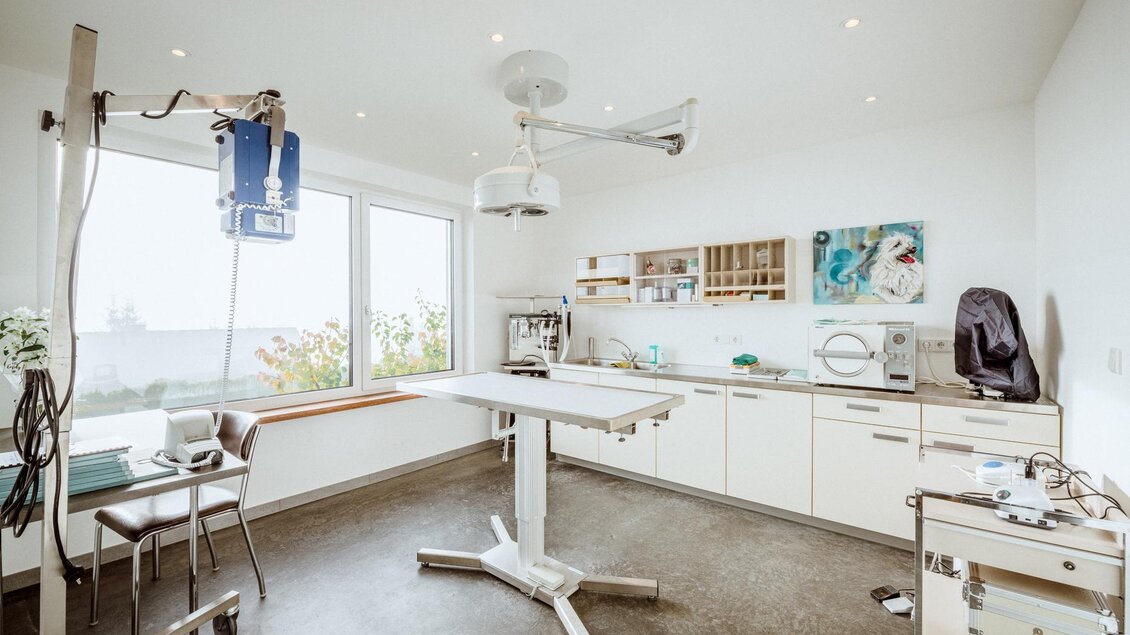 Ein gut ausgestatteter Behandlungsraum mit einem Operationstisch und modernen medizinischen Geräten. Die Wände sind hell und freundlich, mit großen Fenstern, die viel Licht hereinlassen. | © Christoph Huber