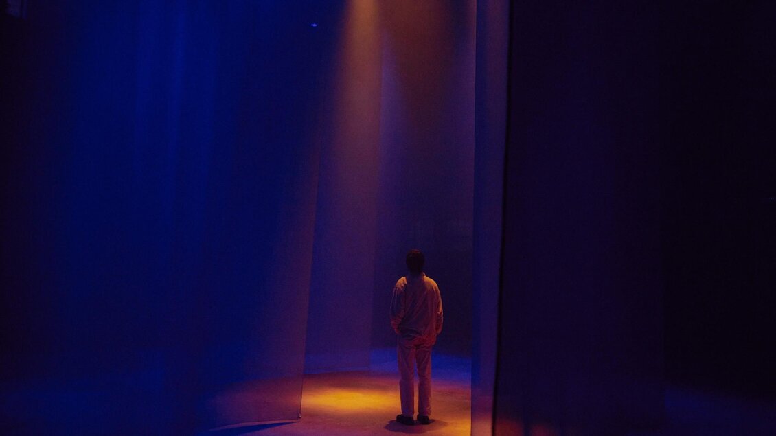 Person steht in Lichtkegel zwischen halbtransparenten Stoffbahnen im Dom im Berg | © Iris Humm