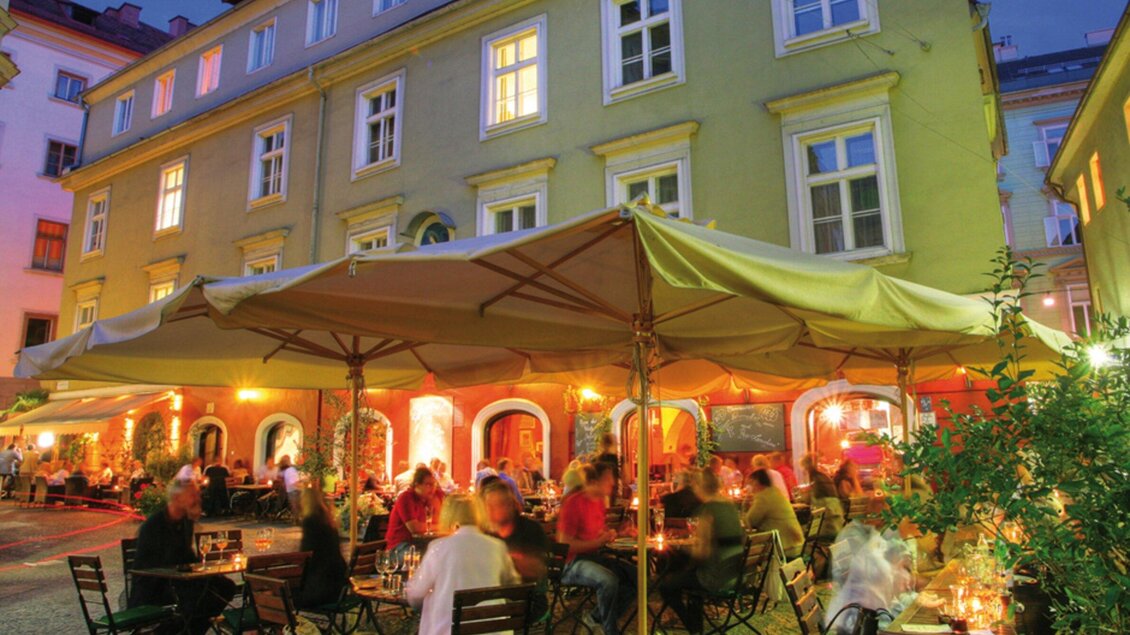 Ein gemütliches Restaurant mit einer überdachten Terrasse bei Nacht. Die Atmosphäre ist lebhaft, mit vielen Gästen und warmem Licht. | © Don Camillo