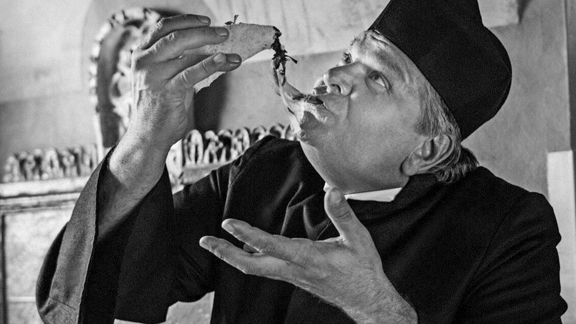 Ein Mann in traditioneller Kleidung genießt ein Essen und schaut fasziniert. Er hält eine Speise in der Hand und hat einen begeisterten Ausdruck im Gesicht. | © Don Camillo