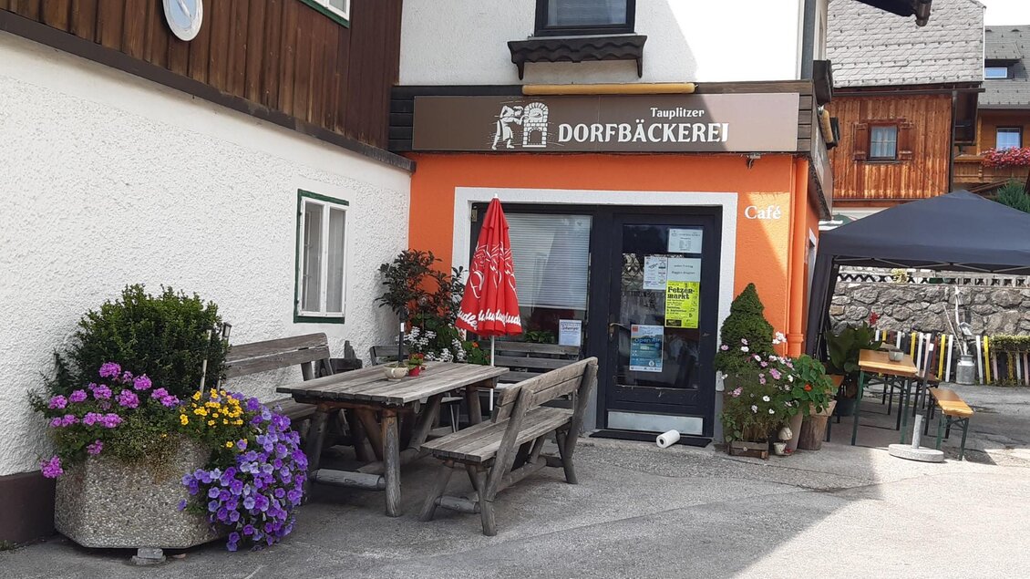 Eine kleine Bäckerei mit einem einladenden Eingang und Tischen im Freien. Bunte Blumen schmücken den Bereich vor dem Geschäft. | © TVB Ausseerland Salzkammergut/Raunigg